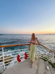 a woman standing on top of a boat near the ocean