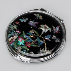 a compact case with butterflies and flowers painted on the inside is shown in silver, black, and white