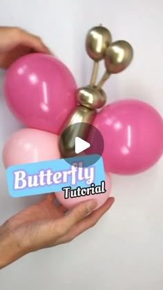 someone is holding some pink and gold balloons in front of a white wall with the words butterfly on it