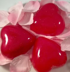 three heart shaped candies sitting on top of pink tissue paper with leaves around them