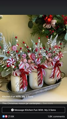 three mason jars filled with candy canes and greenery are sitting on a tray