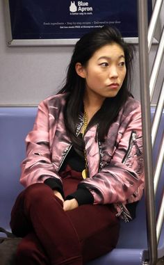 a woman sitting on a train seat with her arms crossed and looking off to the side