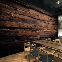 a large wooden table sitting in front of a window next to a wall with wood planks on it