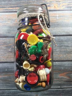 a glass jar filled with lots of different types of plastic toys on top of a wooden table