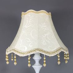 a lamp that is on top of a table with a white base and gold trimmings