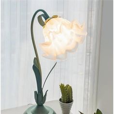 a white flower sitting on top of a table next to a green potted plant