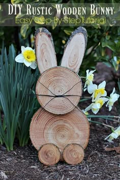 a wooden bunny sitting on top of a pile of wood next to daffodils