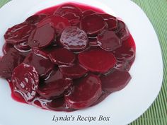 a white plate topped with sliced beets covered in red sauce on top of a green place mat