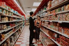 a man and woman standing in the aisle of a grocery store