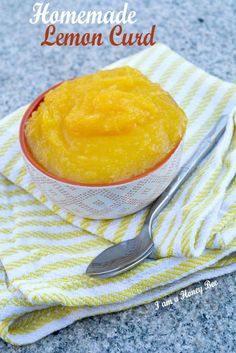 homemade lemon curd in a bowl on a yellow and white towel with a spoon