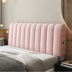 a pink headboard on top of a bed next to a night stand and mirror