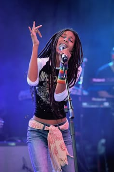 a woman with dreadlocks singing into a microphone