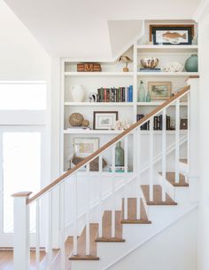 a white staircase with bookshelves and pictures on the wall