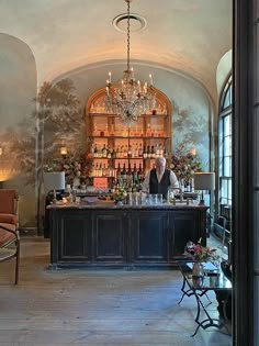 a man behind the bar in a fancy restaurant with chandelier hanging from the ceiling