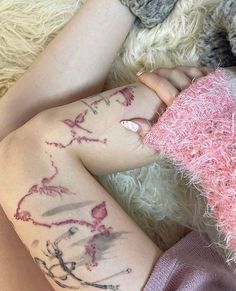 a person with tattoos on their legs laying next to a teddy bear and fuzzy blanket