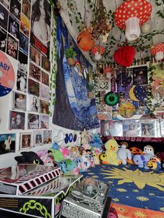 a room filled with lots of stuffed animals and pictures on the wall above it is a bed covered in colorful blankets