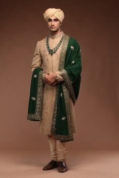 a man dressed in green and white standing with his hands on his hips wearing a turban