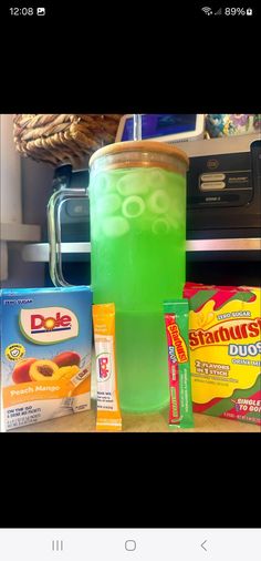 a green drink sitting on top of a table next to some snacks and other items