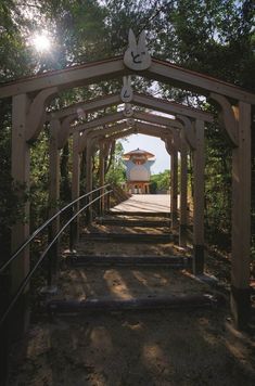 a wooden structure with stairs leading up to it and a pagoda in the background on a sunny day