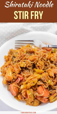 a white bowl filled with noodles and vegetables on top of a table next to a fork