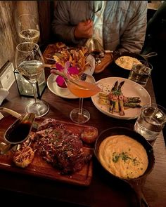 a wooden table topped with plates of food and drinks