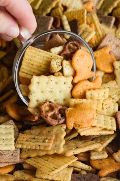 someone is dipping crackers into a bowl of cheetos and pretzels