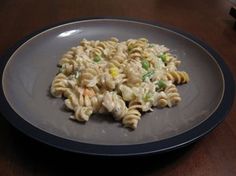 a plate that has some kind of pasta on it with peas and carrots in it