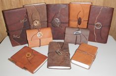 several different types of leather notebooks on a white table with wood panel behind them