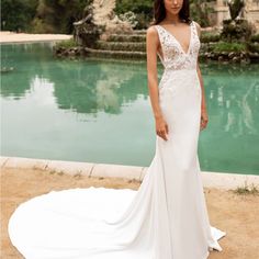 a woman standing in front of a lake wearing a wedding dress