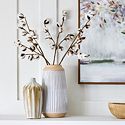 two vases with flowers in them sitting on a shelf next to a painting and other items