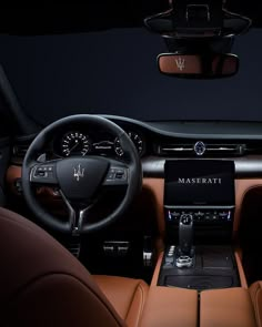 the interior of a maserati car with brown leather seats and steering wheel controls