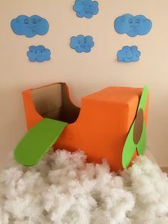 a cardboard airplane sitting on top of foam in a room filled with white fluffy clouds