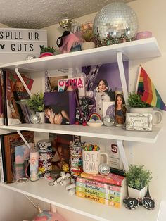 a white shelf filled with lots of books and other items next to a mirror on the wall