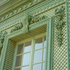 an ornate green window on the side of a building