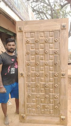 a man standing in front of a wooden door that is carved into the side of a building