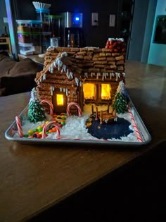 a gingerbread house decorated with candy canes and candies on a silver platter