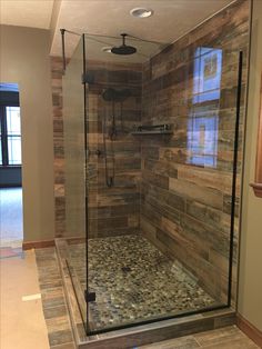 a walk in shower sitting inside of a bathroom next to a window and tiled floor