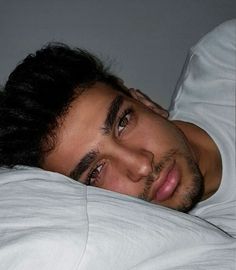 a man laying in bed with white sheets