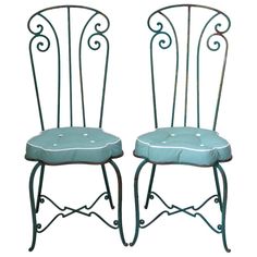 pair of wrought iron chairs with blue upholstered seat cushions and white piping