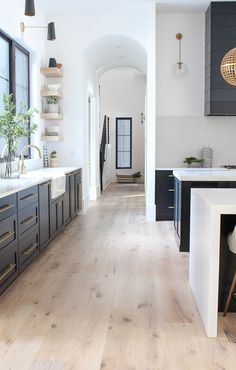 a large kitchen with wooden floors and black cabinets, along with white counter tops on both sides