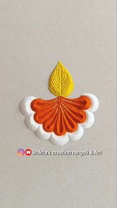 an orange and yellow leaf on top of a white background with the words nikka's creation rangoli & art