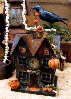 a bird house is decorated with pumpkins and greenery