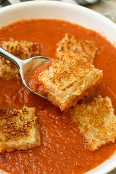 a white bowl filled with tomato soup and bread croutons on top of it