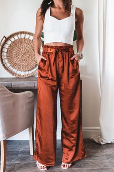 Step into the season with some serious style! Our Jade Wide Leg Pants will take your look from summer to fall with ease. Plus, you can mix and match these pants with any top for endless stylish possibilities! Wear 'em to work, on an errand, to dinner, anywhere! 97% Polyester 3%Spandex Satin Like fabric Color: Deep Rust High waisted Pants Light weight Straight Leg Half Elastic waist band Half front self tie sash (non-removable) Side Pockets No button or zipper closure True to size Model is wearin Colorful Pants Outfit, Satin Pants Outfit, Satin Wide Leg Pants, Mom Outfits Fall, Satin Pants, Fashion Business Casual, Summer To Fall, Colored Pants, Mom Outfits