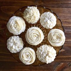 cupcakes with white frosting are arranged in a circle on a brown plate