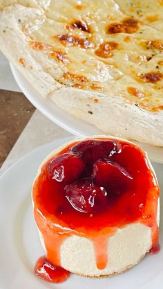 there is a cheesecake with strawberry sauce on the plate next to it and another pie in the background