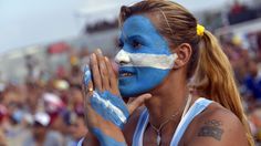 a woman with her face painted blue and white at a sporting event in front of a crowd