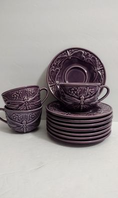 a stack of purple dishes sitting next to each other on top of a white table