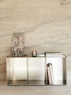 a book shelf with two books on it in front of a wall that is made out of concrete