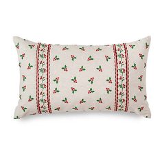 a white pillow with red trimmings and holly leaves on it, against a white background